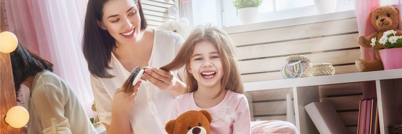 A mother brushing her daughter's hari