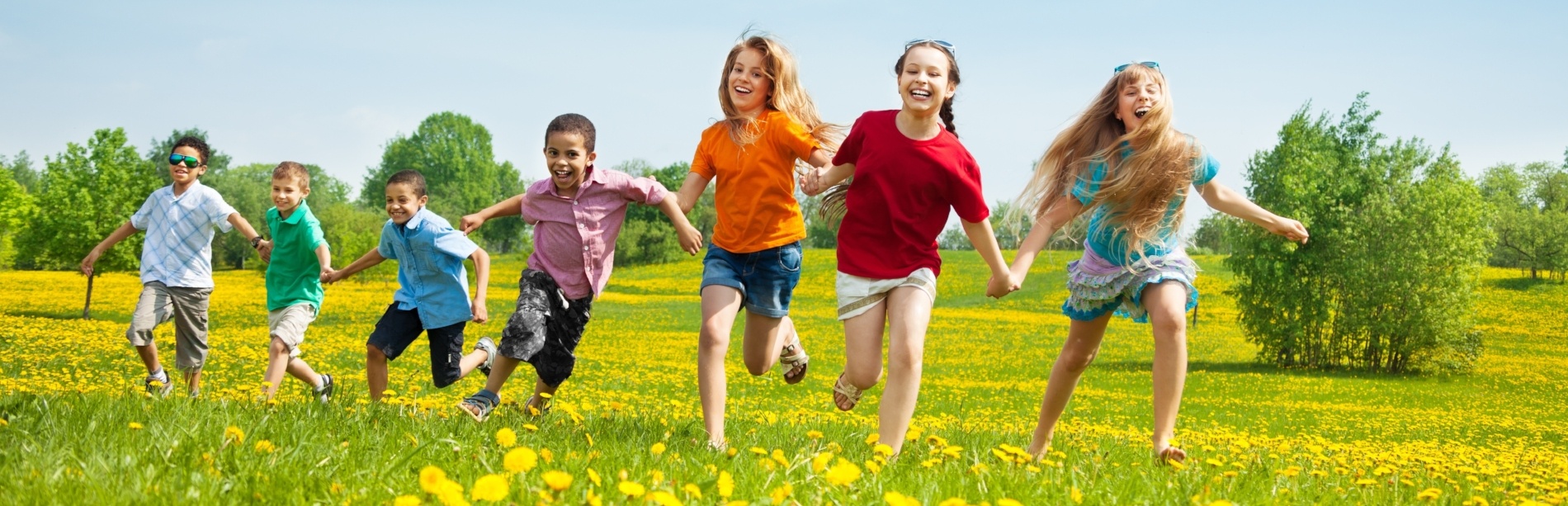 Children playfully running through a field of dandelions