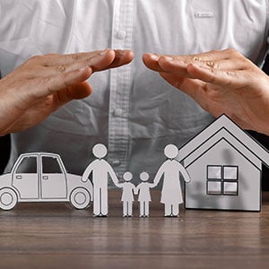 Hands covering a family, their car, and their home